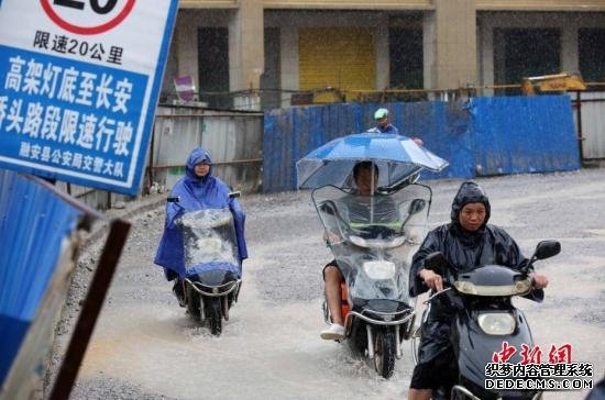 民众穿着雨衣骑电动车出行。谭凯兴 摄